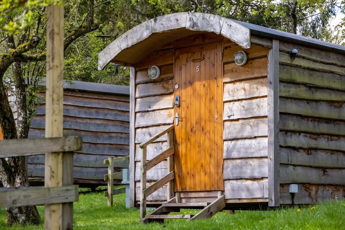 A wooden cabin with a wooden door and a small porch.