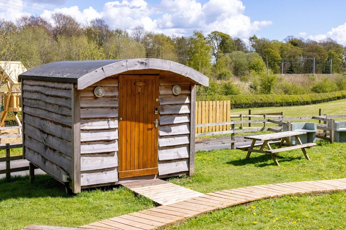 A wooden cabin with a curved roof, a door, and a small porch.
