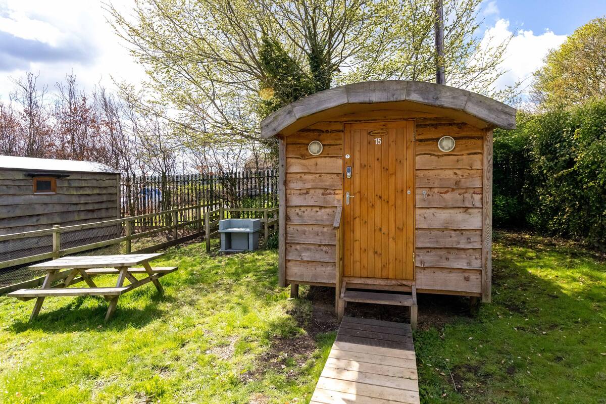 A wooden cabin with a door marked '15', a picnic table, and a wooden deck leading to the cabin.