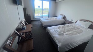 A hotel room with two beds, a desk, a chair, a TV, and an air conditioning unit. - Pension Bigfisher Club (Shimoda)