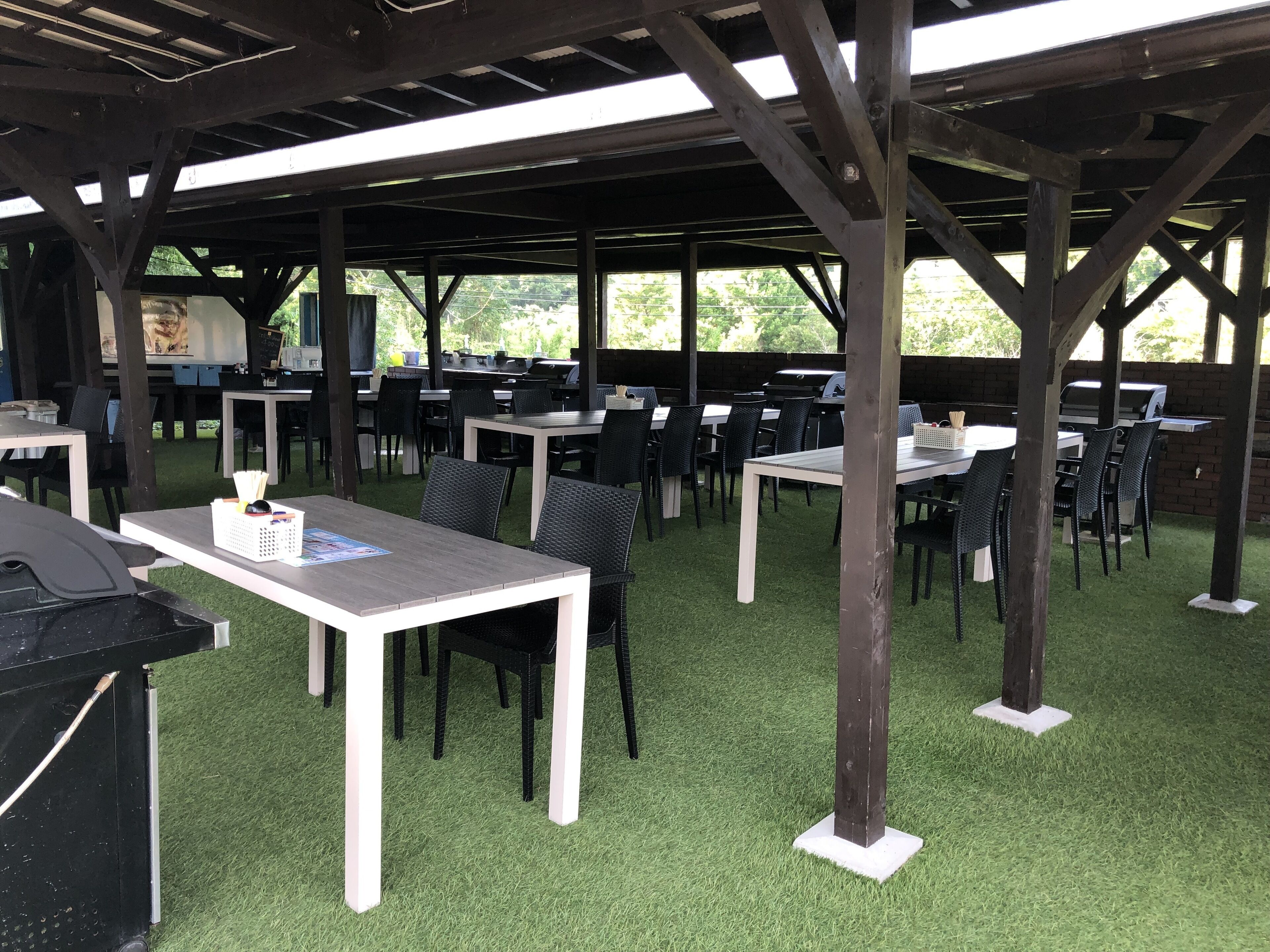 Un patio al aire libre con mesas y sillas, una parrilla y vistas a zonas verdes.