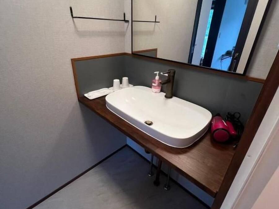 A bathroom with a white sink, a mirror, and a wooden vanity.