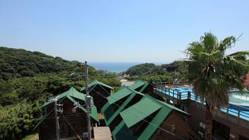 Vista de un complejo turístico con varias cabañas, una piscina y vistas al océano.
