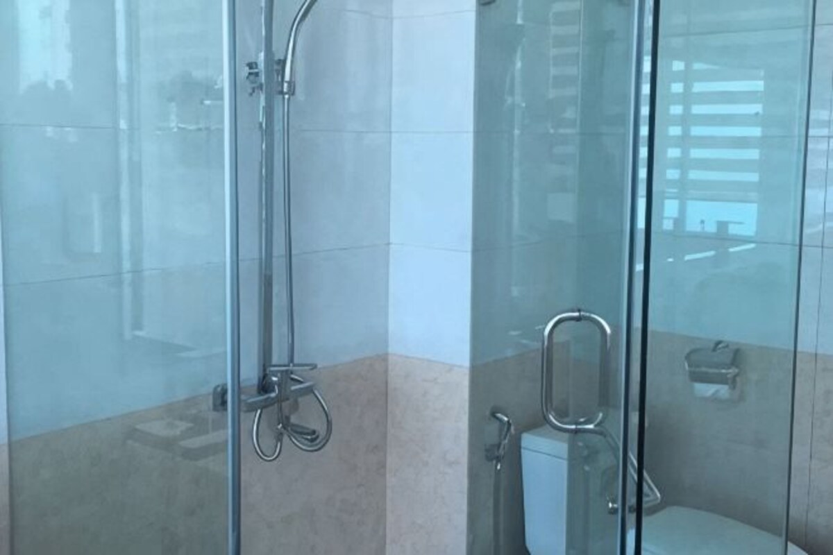 A glass-enclosed shower area with a metal showerhead and a glass door.