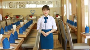 Un restaurant avec de longues tables, nappées de serviettes bleues et de vaisselle blanche.