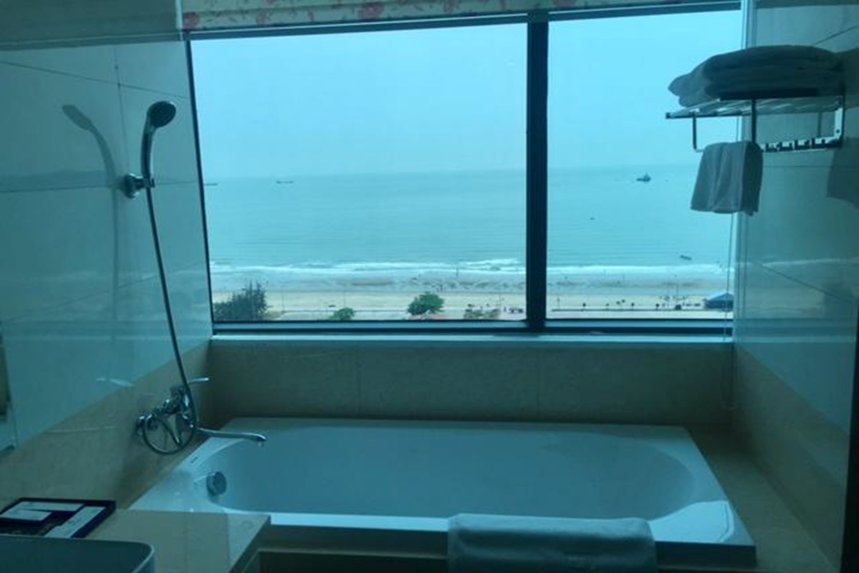 A bathroom with a large window offering a view of the beach and ocean.