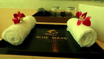 Dos toallas blancas con flores rojas sobre una bandeja con el logotipo del Hotel Blue Wave.