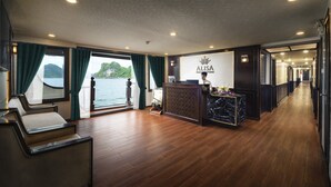Un espace d’accueil doté d’un plancher en bois, d’un comptoir de réception et offrant une vue sur la mer.