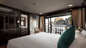 Une chambre d’hôtel dotée d’un grand lit, d’un balcon offrant une vue sur les falaises, d’un coin salon avec un fauteuil et une table, et d’un téléviseur fixé au mur.