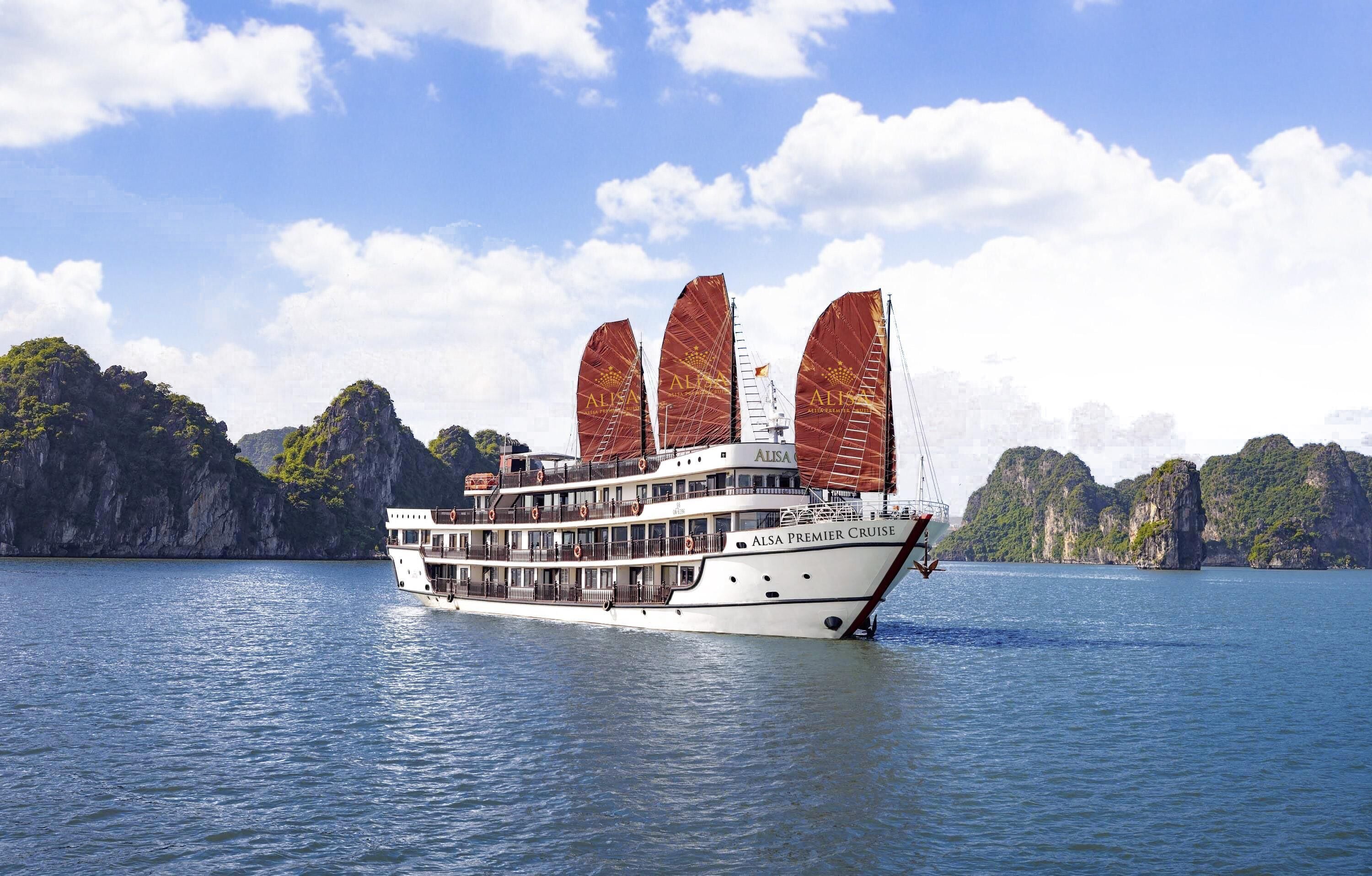 A large cruise ship with multiple decks and a white hull, sailing in a body of water with mountainous terrain in the background.