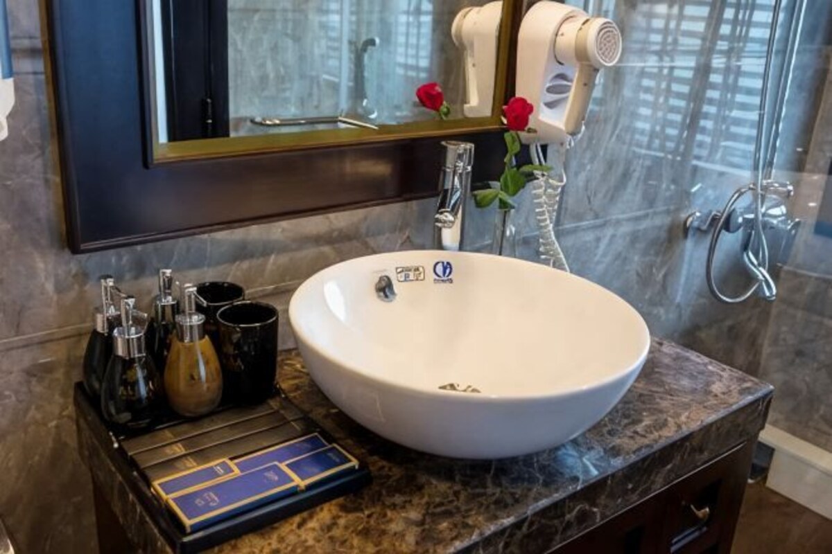 A bathroom with a white sink, a mirror, a hairdryer, and a towel rack.