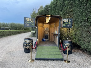 Un espace d’enregistrement automatisé avec un intérieur en bois, une statue et deux barils portant l’inscription « Willow Court Farm ».
