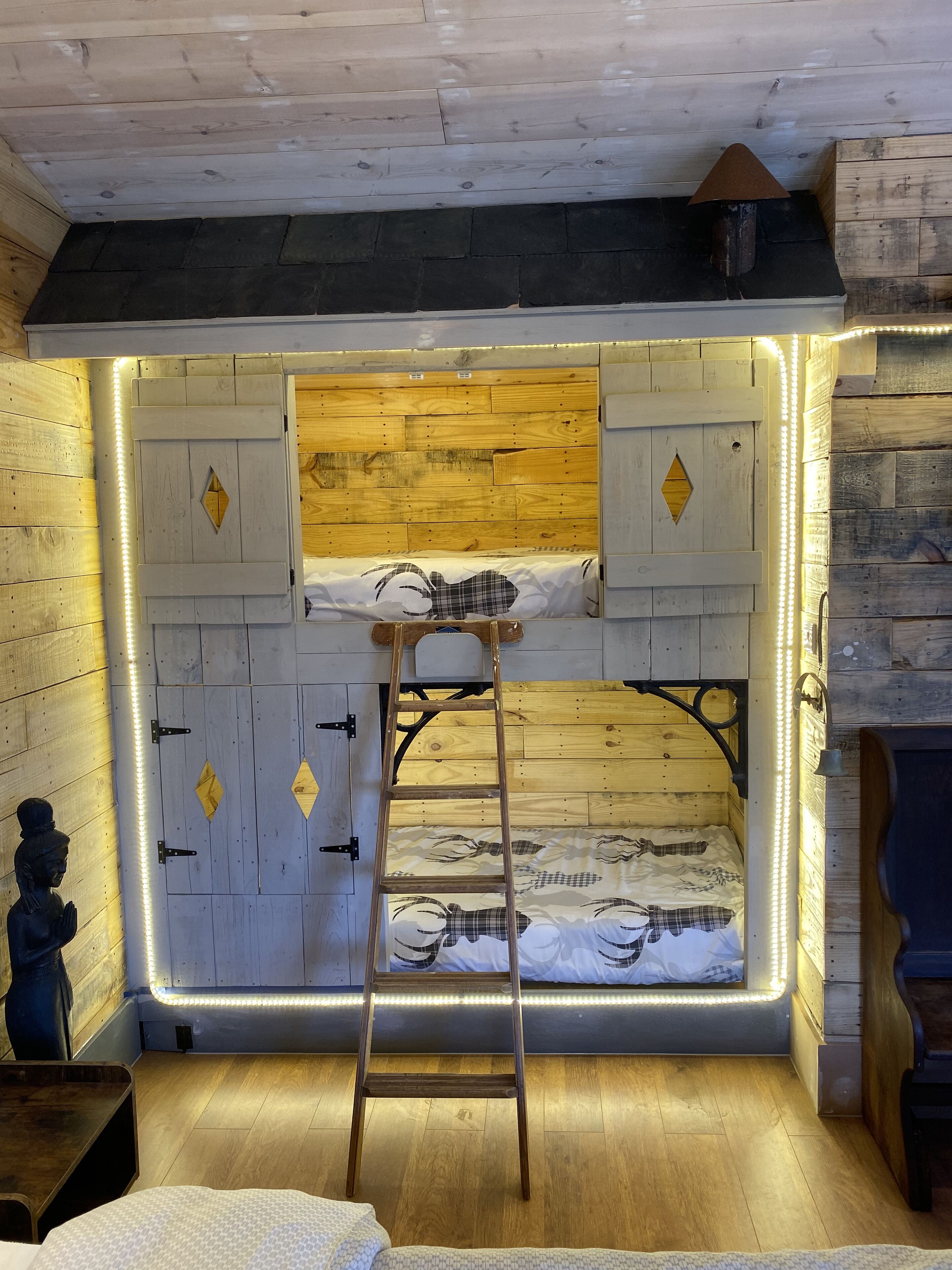 Une pièce chaleureuse avec un lit superposé, des murs en bois et une échelle.