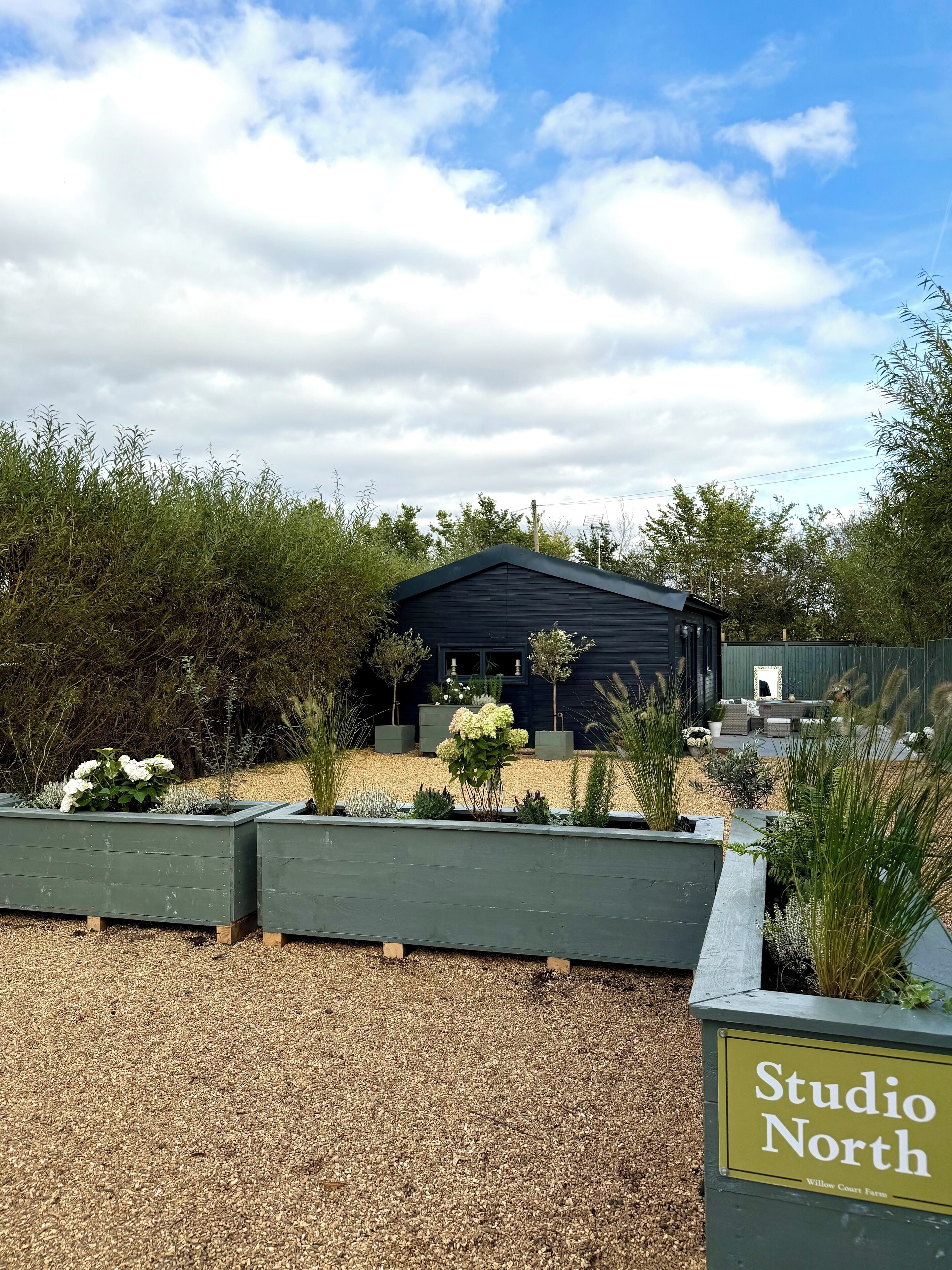 A building labeled "Studio North" with a gravel driveway and landscaped garden beds.