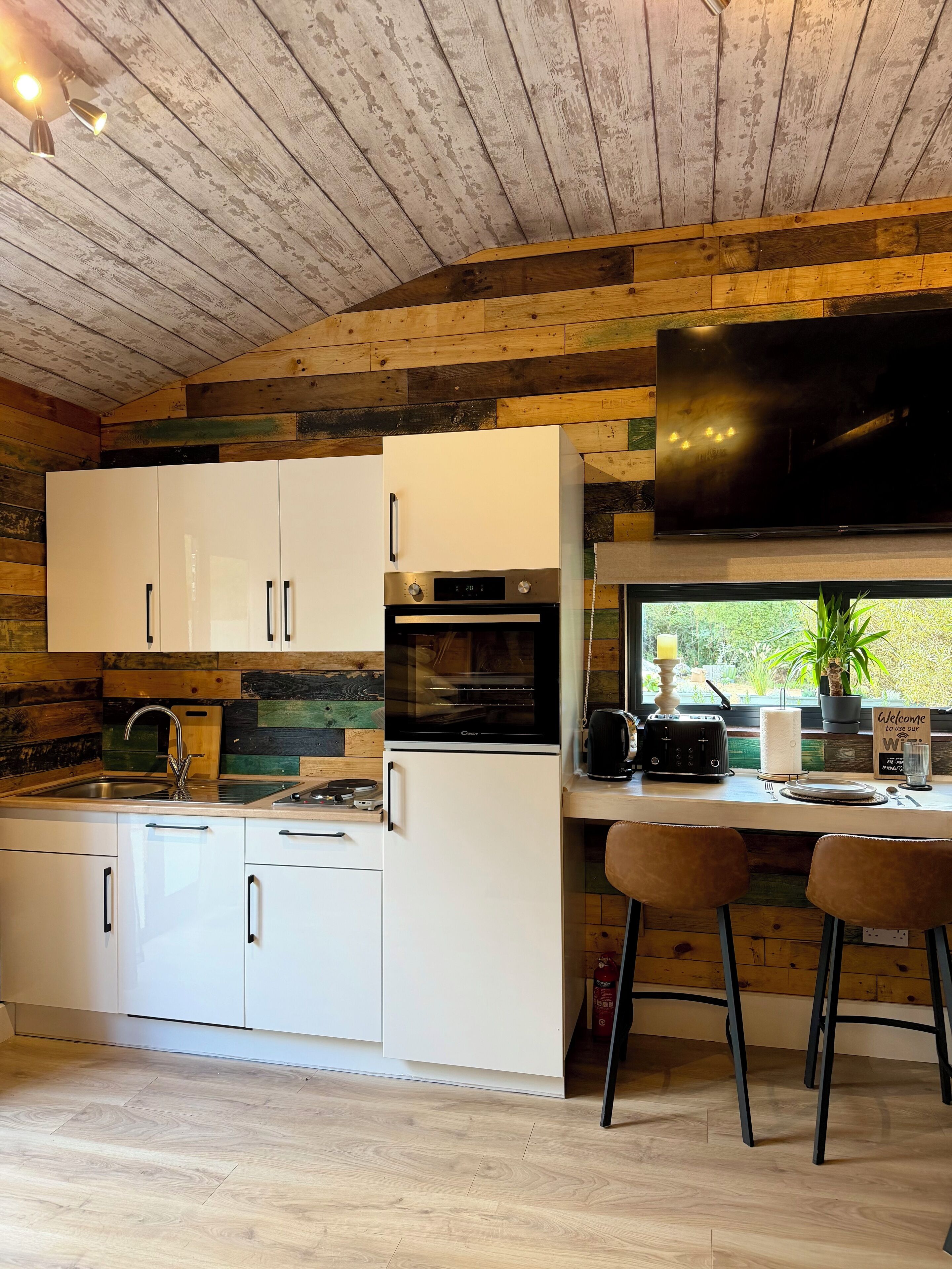 A modern kitchen with white cabinets, a built-in oven, and a large window.