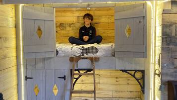 Een stapelbed met een ladder, houten wanden en LED-verlichting.
