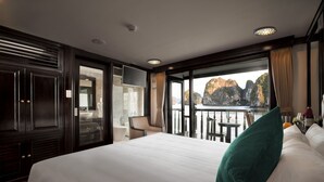 Hotelkamer met een groot bed, een televisie, een balkon met uitzicht op kliffen en een zithoek.