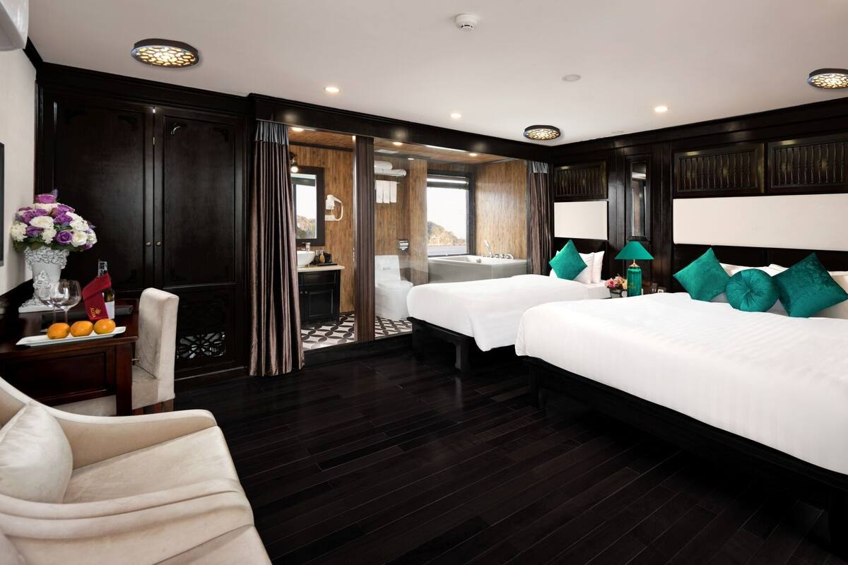 A hotel room with two beds, a sitting area with a chair, a vanity with a mirror, and a view of the outdoors.
