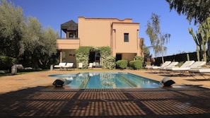 Una piscina al aire libre, sombrillas, tumbonas