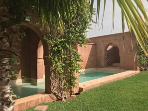 Una piscina al aire libre, sombrillas, sillones reclinables de piscina