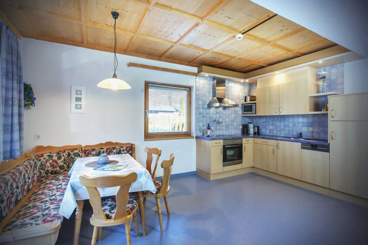 Una cocina acogedora con armarios de madera, una mesa de comedor con sillas y un horno empotrado.