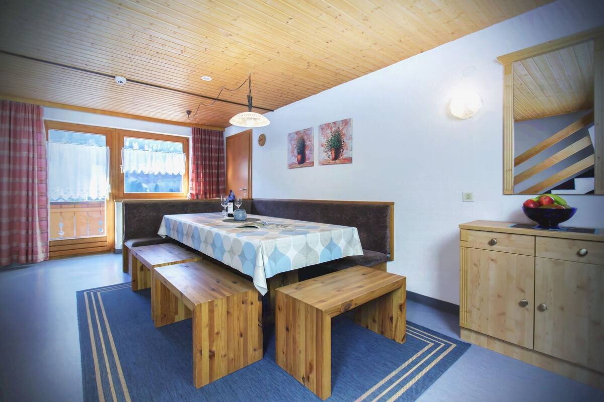 Un comedor acogedor con una mesa de madera, bancos y un asiento tipo banca.