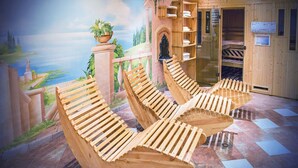 A room with wooden loungers, a mural of a landscape, and a wooden door with shelves. - Gästehaus Rifa (Gaschurn)