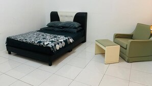 Een slaapkamer met een bed, een groene fauteuil en een klein krukje.