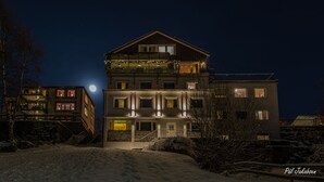 A multi-story building with balconies, a staircase, and a snow-covered ground. - Breidablikk Gjestehus (Narvik)