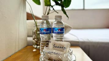 Dos botellas de agua SeaMaster y un jabonero de vidrio con una barra de jabón Saanen sobre una mesa de madera.
