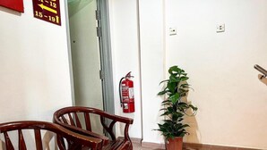 Un pasillo con extintor, planta en maceta y dos sillas de madera.