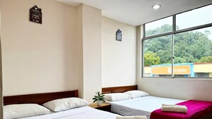 Una habitación de hotel con dos camas, una ventana con vista a zonas verdes y un cartel en la pared.