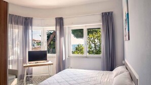 A bedroom with a bed, a desk, and a window with curtains. - Hotel Costa Verde (Rosignano Marittimo)
