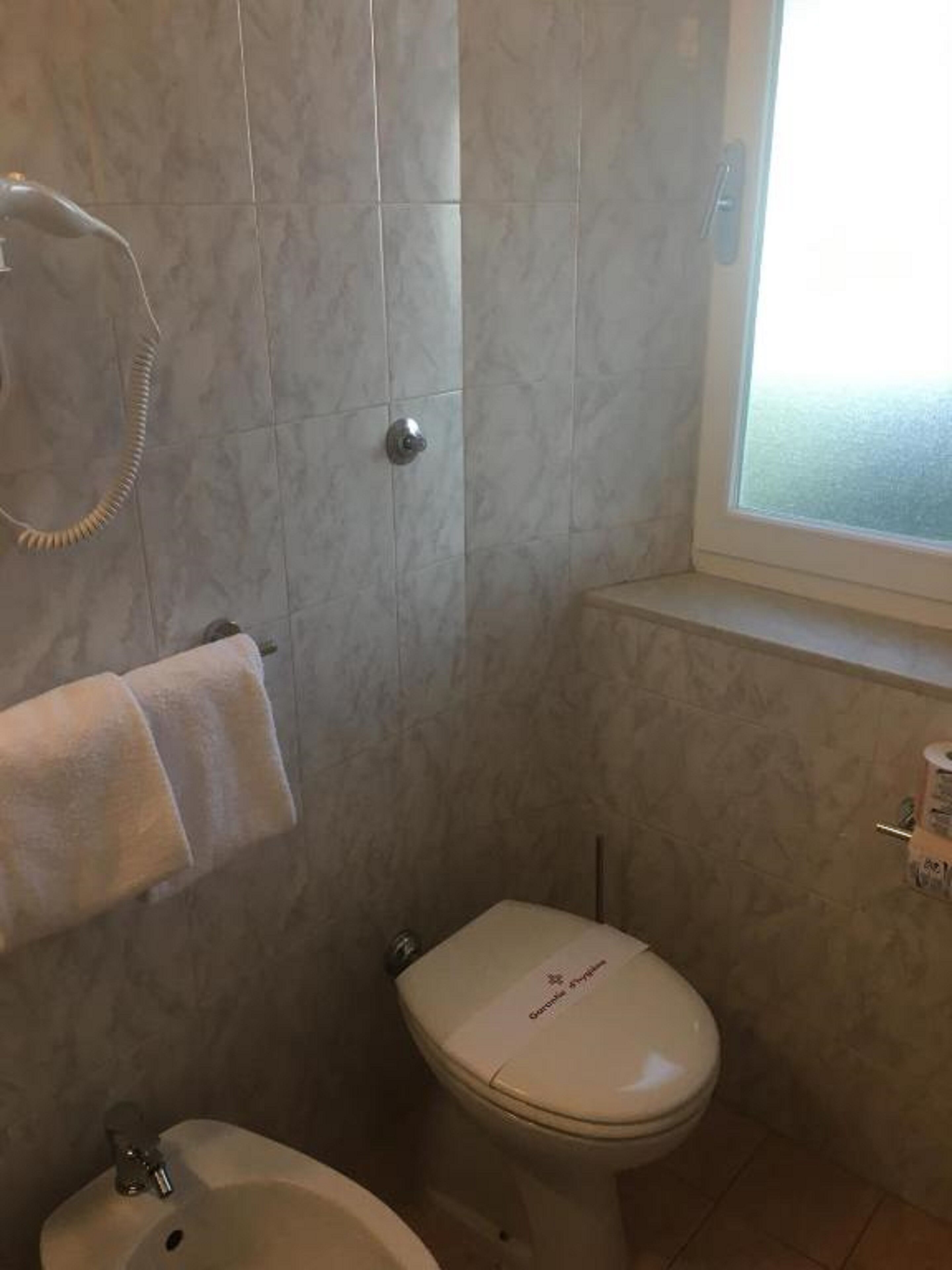 A bathroom with a toilet, bidet, and a towel rack.