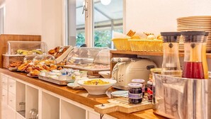 A buffet setup with various food items, a coffee machine, and condiments. - Hotel Costa Verde (Rosignano Marittimo)