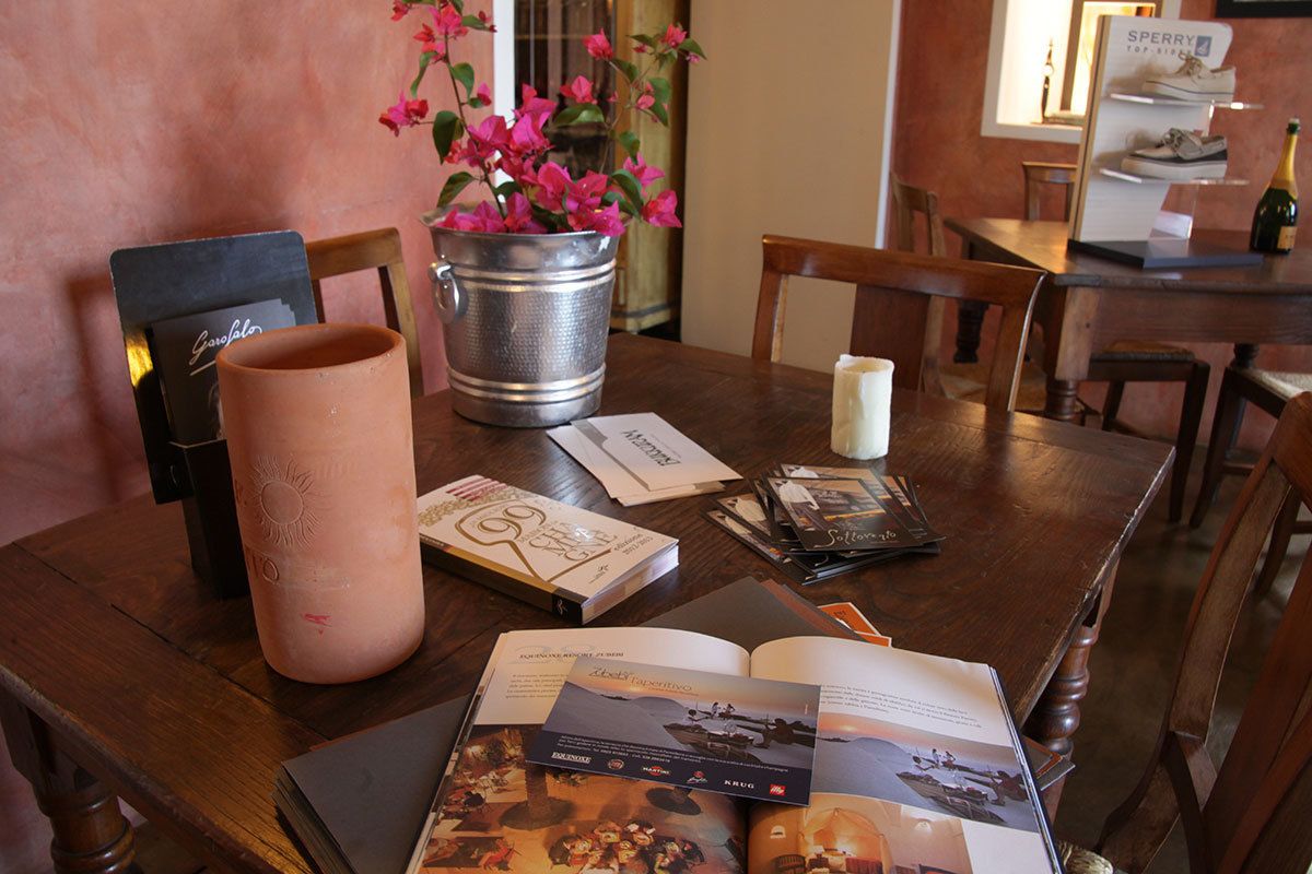 A wooden table with a book, a candle, and a metal bucket with pink flowers.