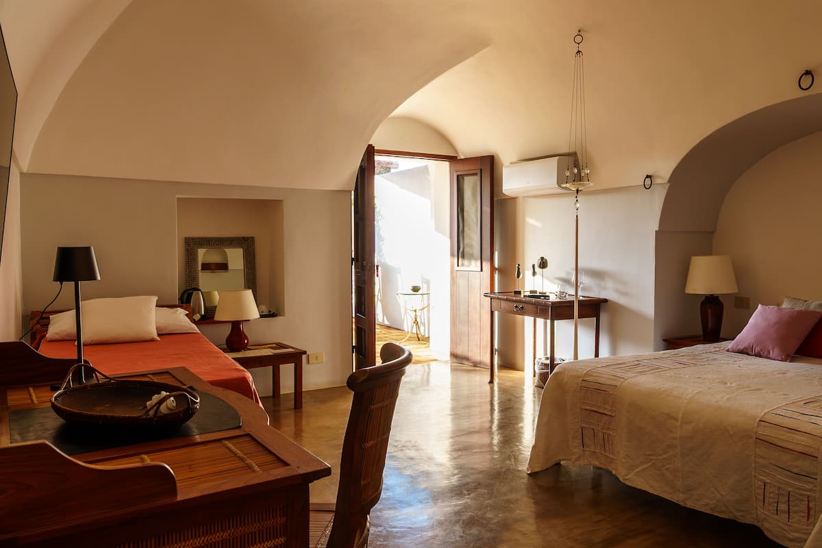 A spacious bedroom with a large bed, a wooden desk, a chair, and a dining table.