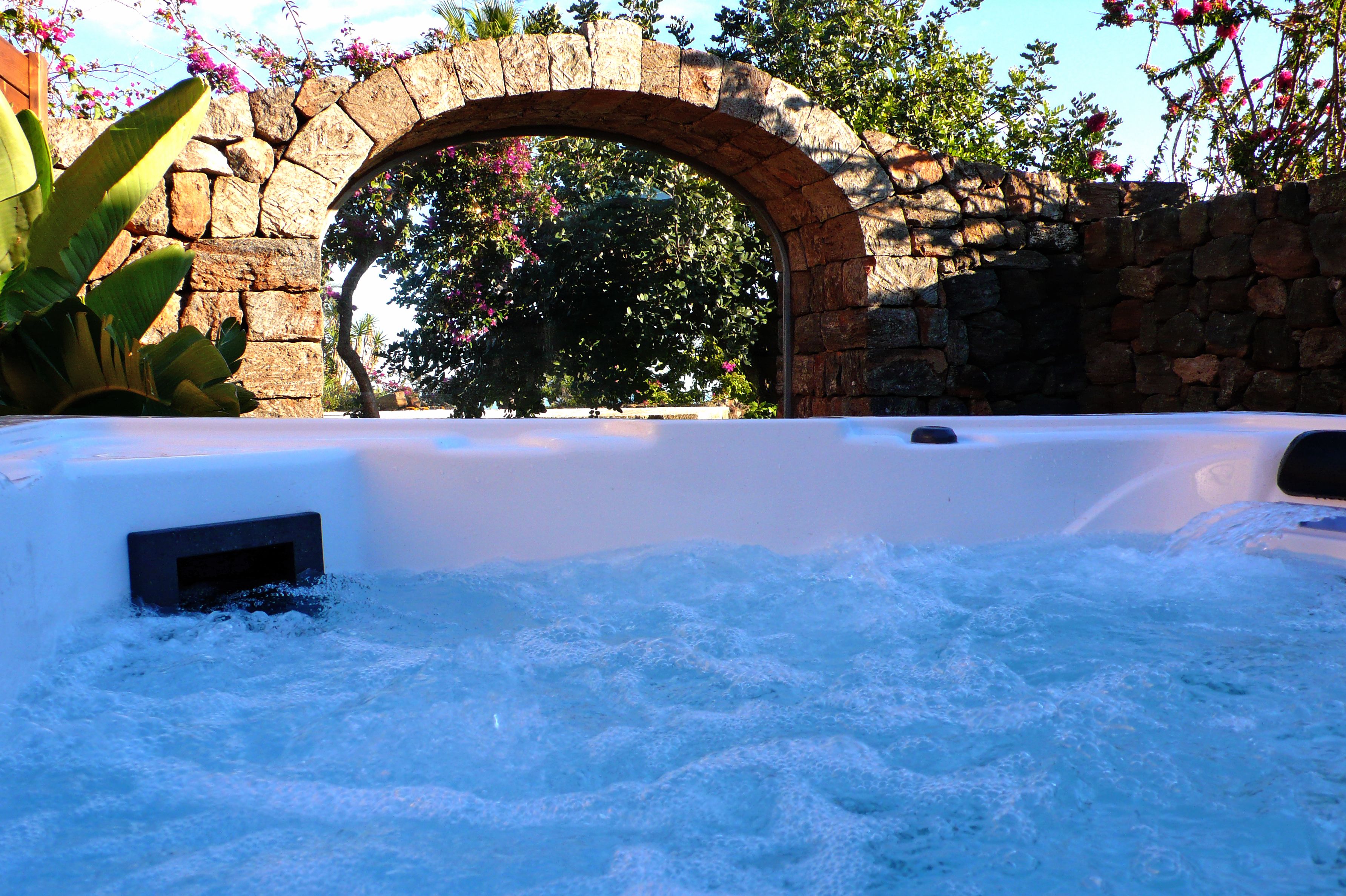A hot tub with a stone archway and lush greenery in the background.