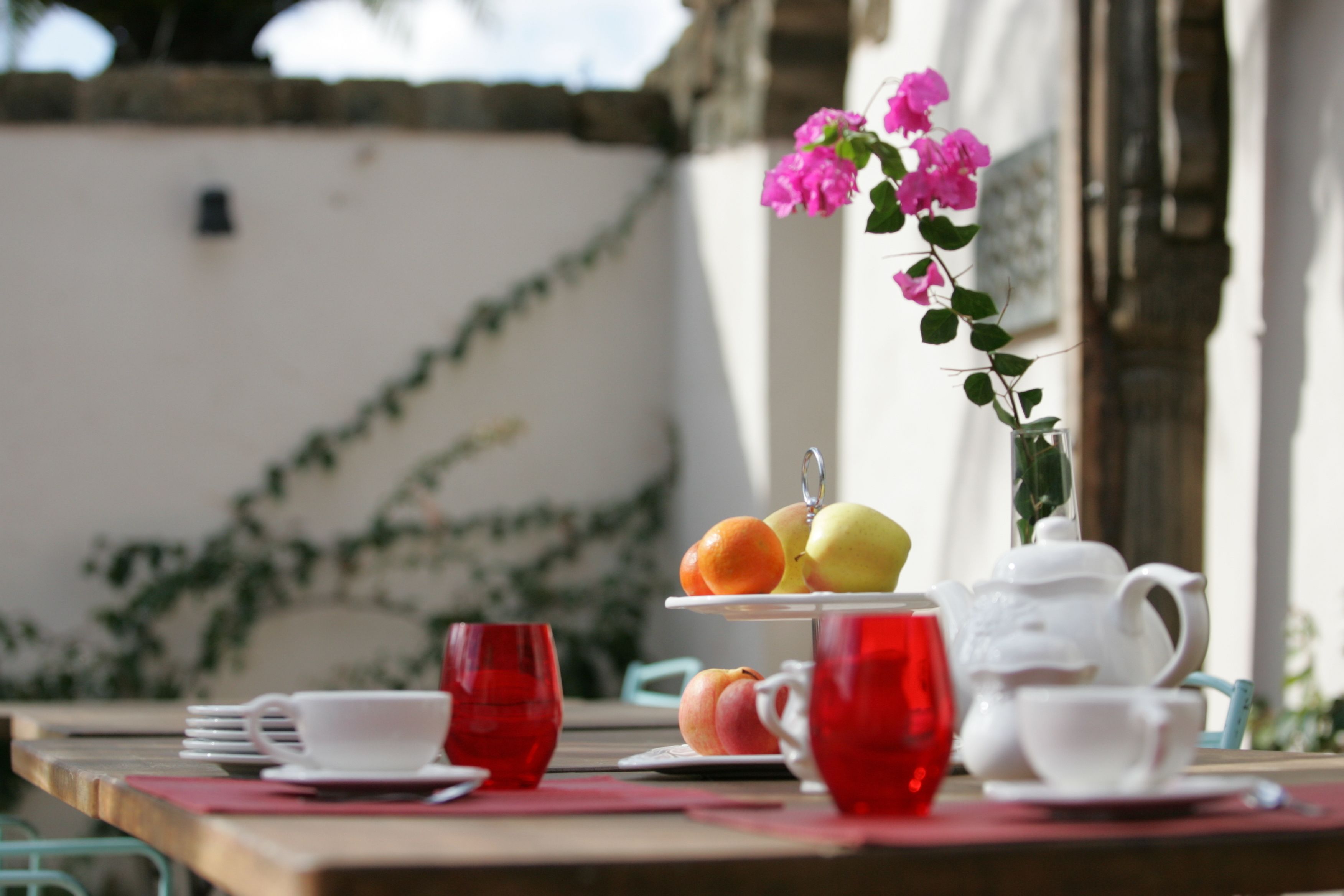 Una mesa servida con tetera, tazas y una bandeja de frutas.