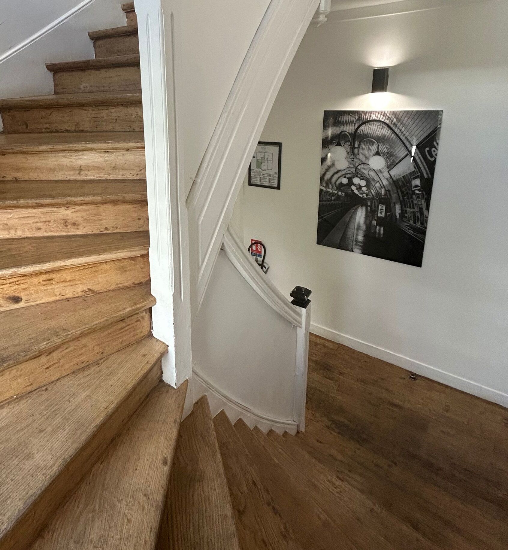 Una scala in legno con modanature bianche e una fotografia in bianco e nero appesa al muro.