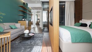 Ein modernes Hotelzimmer mit Bett, Sofa, Couchtisch und Blick auf den Flur.