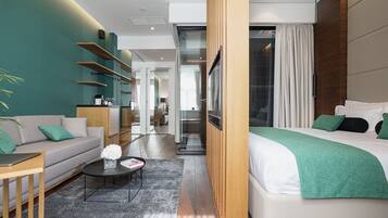 A modern hotel room with a bed, sofa, coffee table, and a view of the hallway.