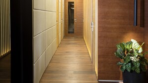 A modern hallway with wooden flooring, recessed ceiling lights, and a potted plant. - Dominic Smart & Luxury Suites Parliament (Belgrade)