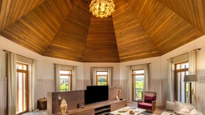 Un salón amplio con techo de madera, televisor de pantalla plana, sofá y una mesa de comedor.