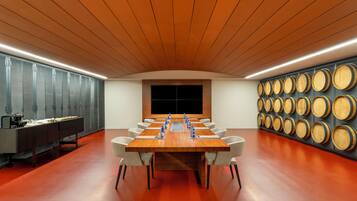 Una sala de conferencias con una larga mesa, sillas, una mesa de buffet y una pared de barriles de madera.