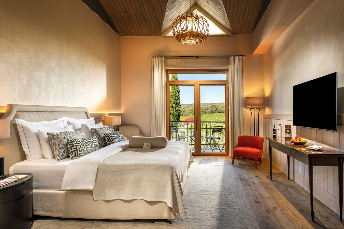 A bedroom with a large bed, a TV, a desk, and a chair.