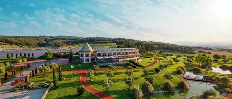 A large, modern hotel with a central courtyard, surrounded by lush greenery and a small pond.