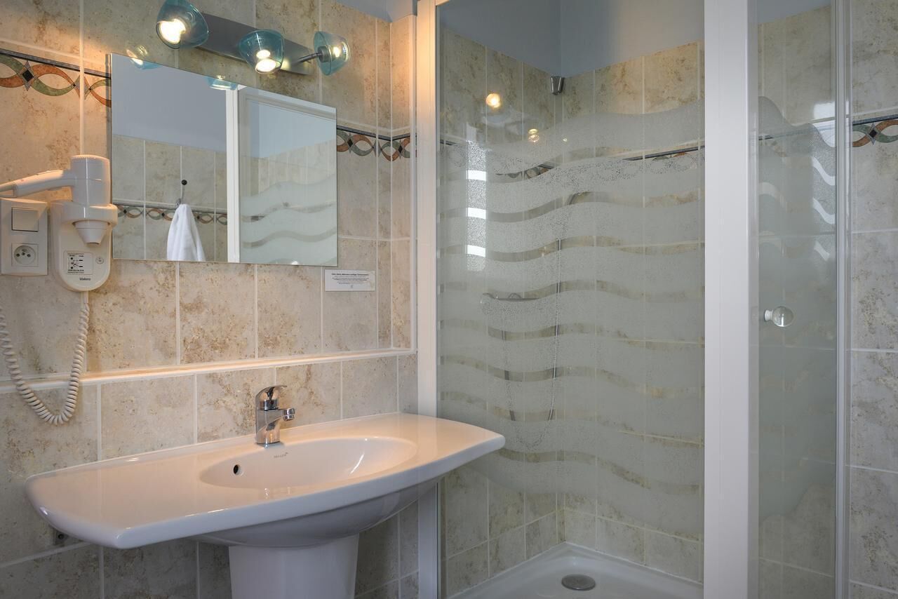 A bathroom with a white sink, a mirror, and a shower with a glass door.