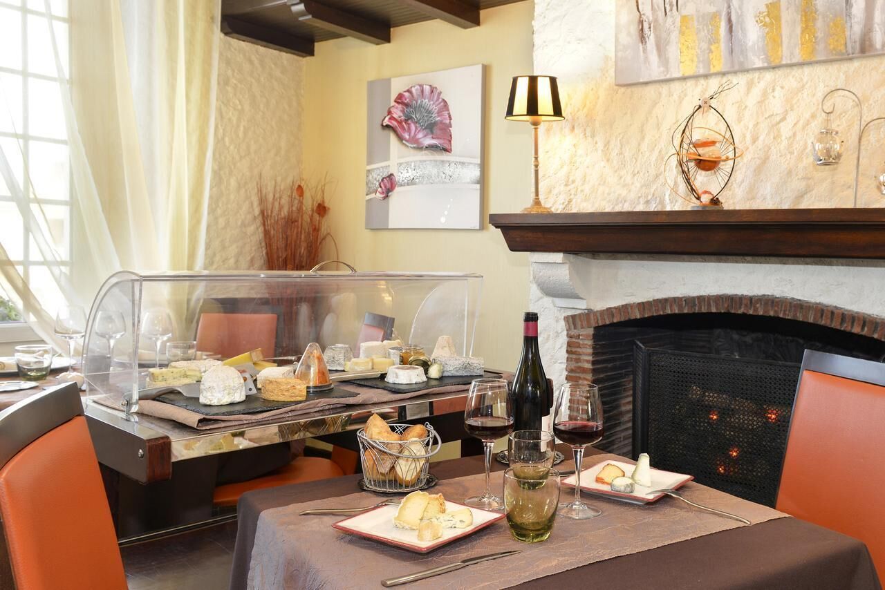 Un restaurant doté d’une cheminée, d’une vitrine transparente où sont exposés les plats, et d’une table dressée pour le repas.