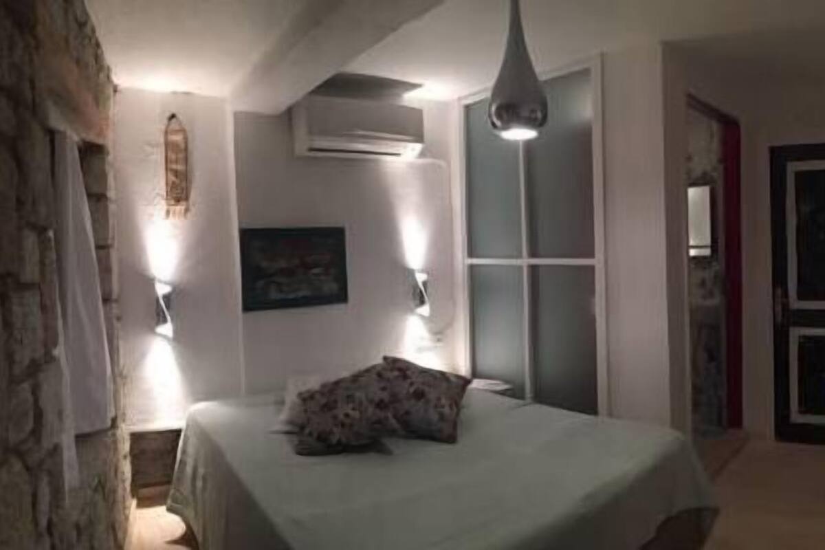 Une chambre à coucher comprenant un lit, une chaise, un climatiseur fixé au mur et une porte.